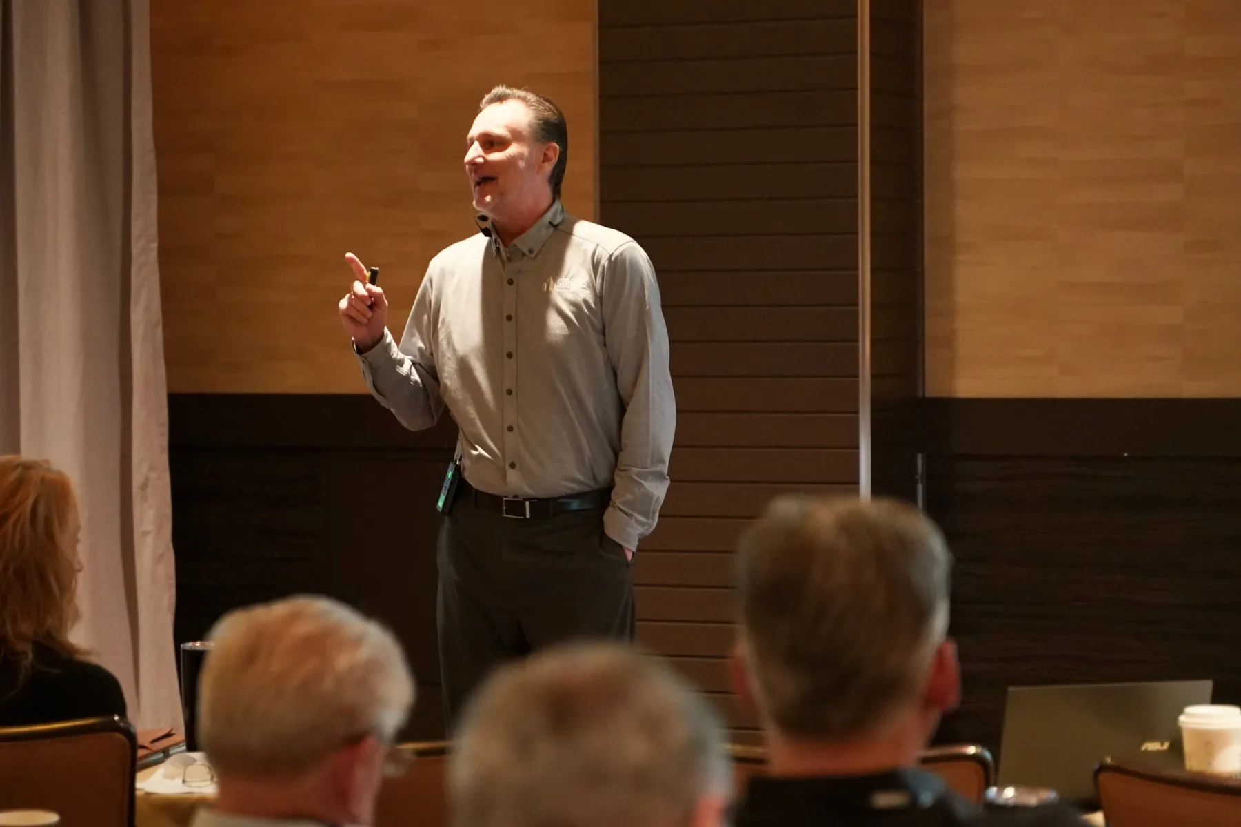 Mike Millett teaching a live audience, raising a finger to emphasize a point